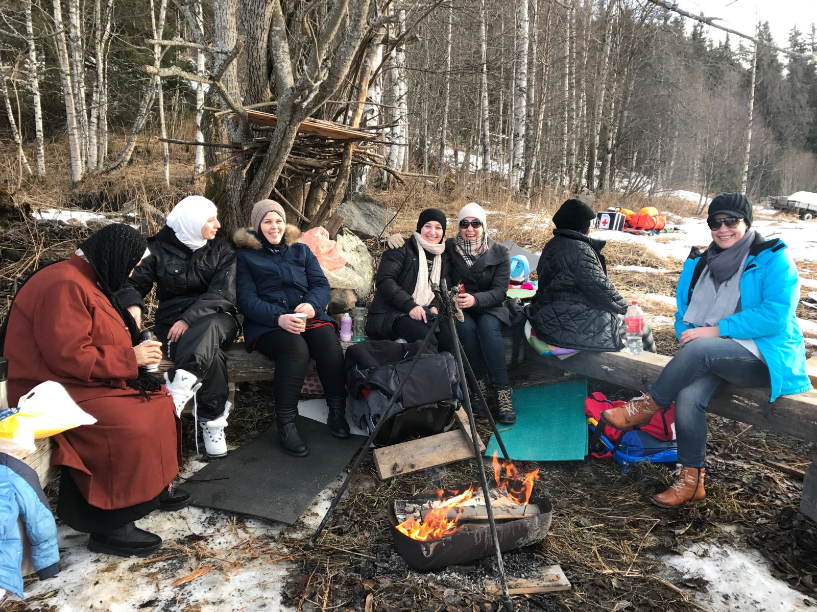 Kvinnene sitter å varmer seg ved bålet